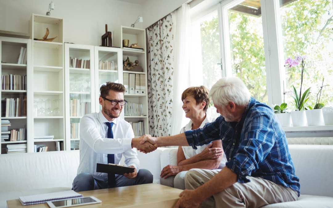 Real estate agent shaking hands with senior man in living room