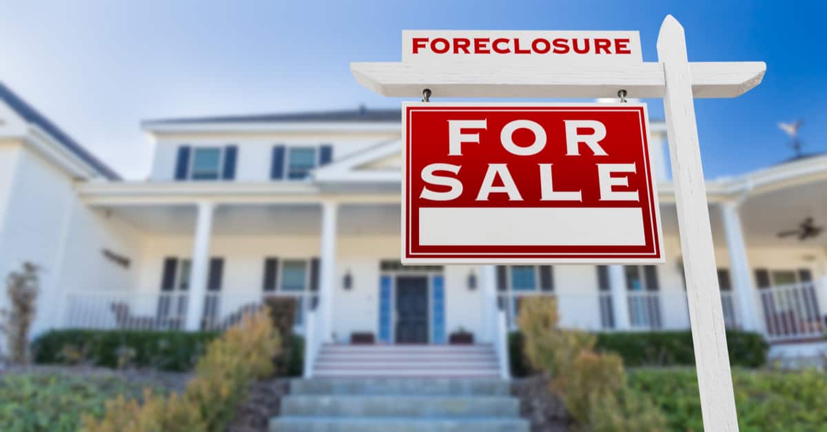 For Sale sign in front of house with Foreclosure sign on top